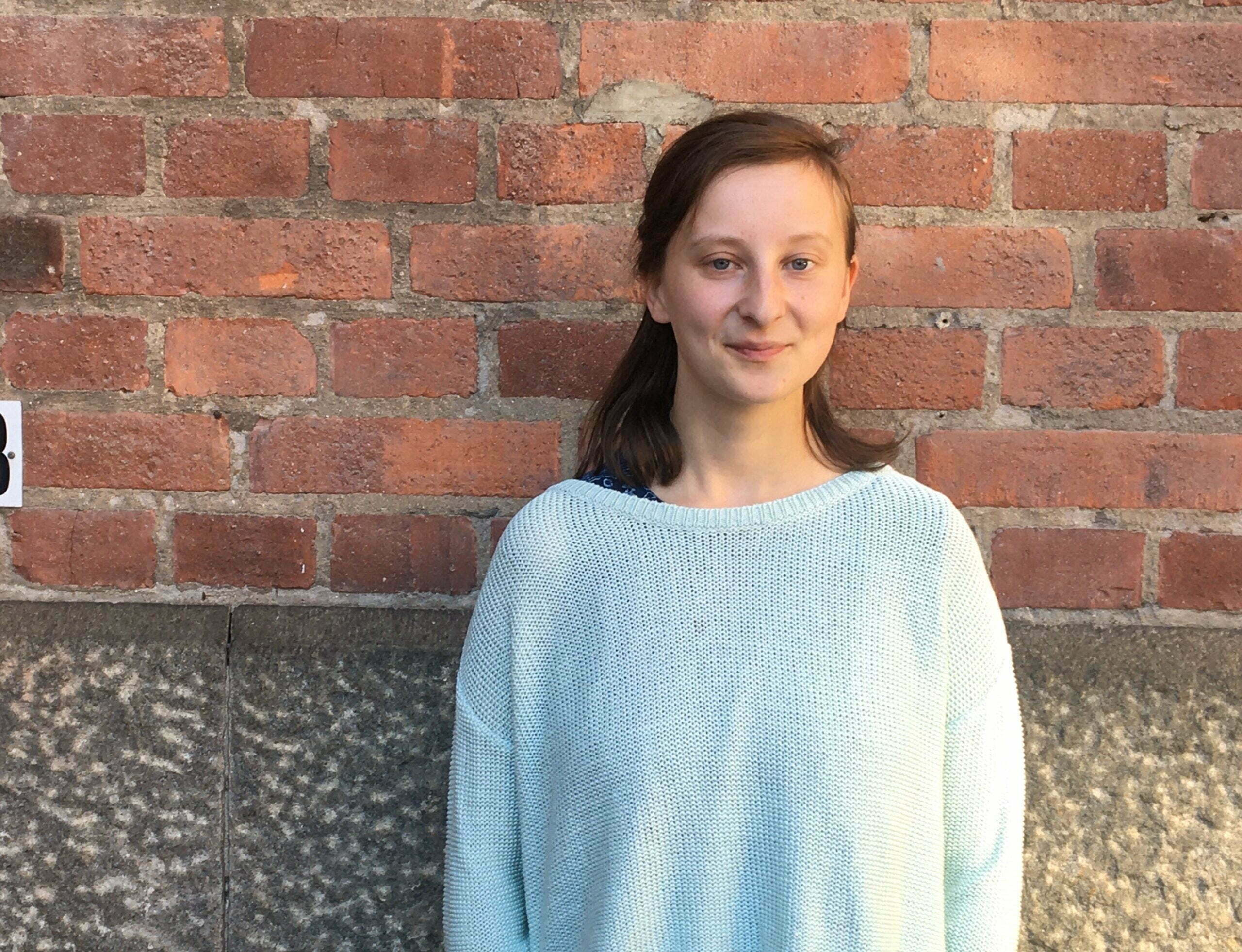 Moa lindholm framför en teglevägg